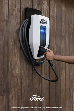 a person is plugging an electric charger into a wooden wall with the word ford on it