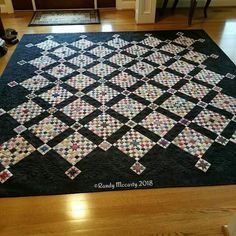 a black and white quilted area rug on top of a hard wood floor in a house