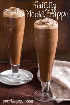 two glasses filled with chocolate drink sitting on top of a table