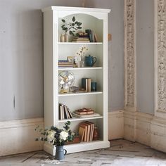 a white bookcase with flowers and books on it