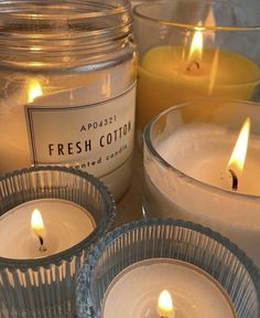 three candles sitting next to each other in front of a glass jar filled with liquid