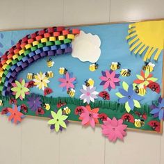 a bulletin board with flowers, bees and a rainbow made out of construction paper on it