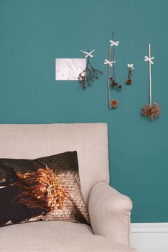 a couch with a pillow on top of it in front of a wall mounted clock