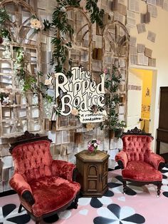 two red chairs and a table in front of a wall