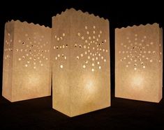 three paper bags with holes on them sitting next to each other in front of a black background