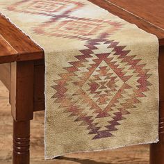 a wooden table with a white and red runner on it's end, next to a wood table