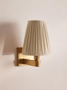 a lamp that is sitting on the wall next to a light fixture with a white lampshade