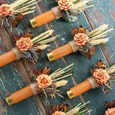 several orange candles with flowers on them sitting on top of a wooden table next to pine cones