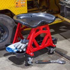 a red and black stool sitting on top of a metal table next to a tool holder