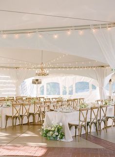 the inside of a tent with tables and chairs set up for a formal dinner party