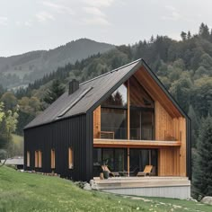 a black house with wooden floors and windows on top of a hill in the mountains