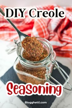 a jar filled with seasoning sitting on top of a table next to a spoon