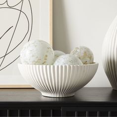 two white vases sitting on top of a table next to an art print and some eggs