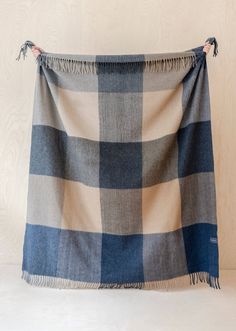 a blue and white checkered blanket with tassels hanging from the side on a wall