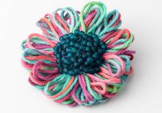 a multicolored flower brooch is shown on a white surface with blue center