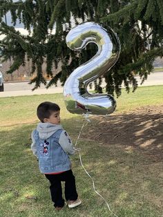 a little boy standing in the grass with a number balloon