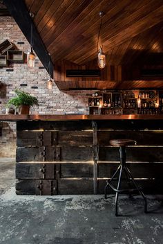 a bar with two stools in front of it and brick walls on the side