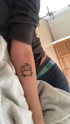 a person with a tattoo on their arm sitting on the floor next to a towel