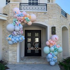 an entrance to a building with balloons all over the front and side door, along with a sign that says balloon