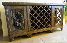 an ornate wooden cabinet with glass doors on the front and bottom, sitting in a room