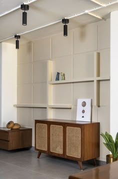 a living room filled with furniture next to a wall mounted book shelf and potted plant