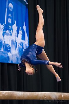 a woman is doing a handstand on the beam