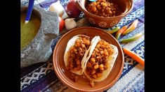 two tacos are sitting on a table with vegetables and other food items around them