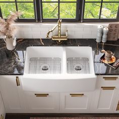 a kitchen with two white double sinks and marble counter tops in front of a window