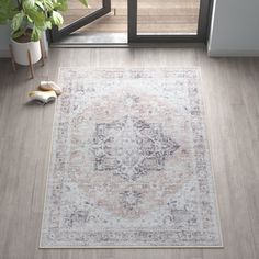 a large area rug with an ornate design in grey and beige colors on a wooden floor