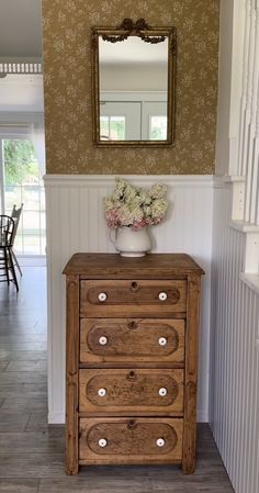 a wooden dresser sitting next to a wall with a mirror on it's side