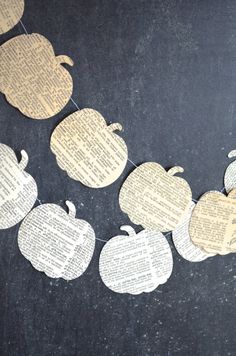 some paper pumpkins hanging from a string on a black surface with words cut out of them