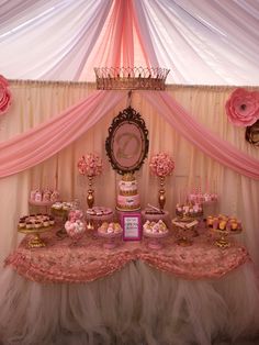 a table topped with lots of desserts under a pink drape covered tented ceiling