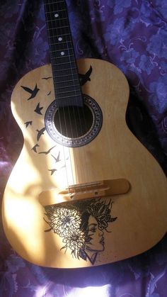 a wooden guitar with an image of a woman's head on the back and sides