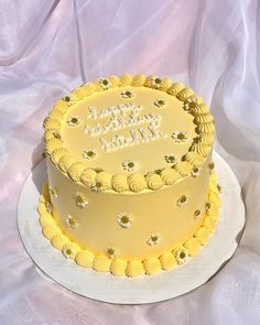 a yellow birthday cake sitting on top of a white plate