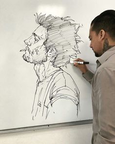 a man writing on a whiteboard with a drawing of a person's head