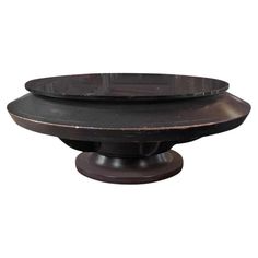 a round wooden table with two plates on it's pedestals and one is black