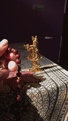 a person holding beads in their hand next to a gold statue on a table cloth