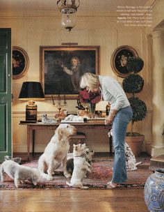 a woman standing in front of a bunch of dogs on the floor next to a table