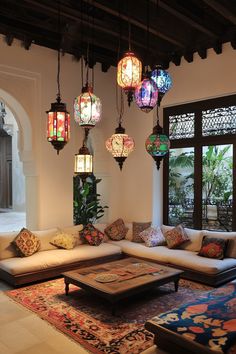 a living room filled with lots of furniture and lamps hanging from the ceiling above it