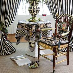 a dining room table with black and white checkered cloths on it, next to two chairs