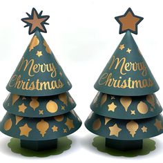 two green christmas trees with gold stars and merry lettering on them, sitting side by side