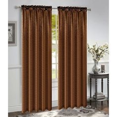 a living room with a window covered in brown curtains and a rug on the floor