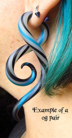 a woman with green hair wearing earrings made to look like swirls on her ear