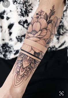 a woman's arm with a flower and ribbon tattoo on her left arm,