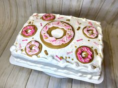 a white cake with pink frosting and sprinkles on it sitting on top of a wooden table