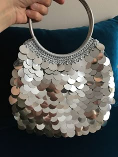 a hand holding a purse made out of silver coins