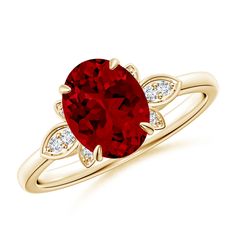 a ring with a red stone and two white diamonds on the side, set in yellow gold