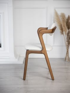 a white chair sitting on top of a wooden floor next to a vase filled with flowers