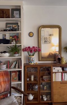 a living room filled with furniture and a large mirror on top of a book shelf