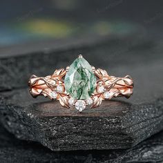 a green and white diamond ring sitting on top of a rock